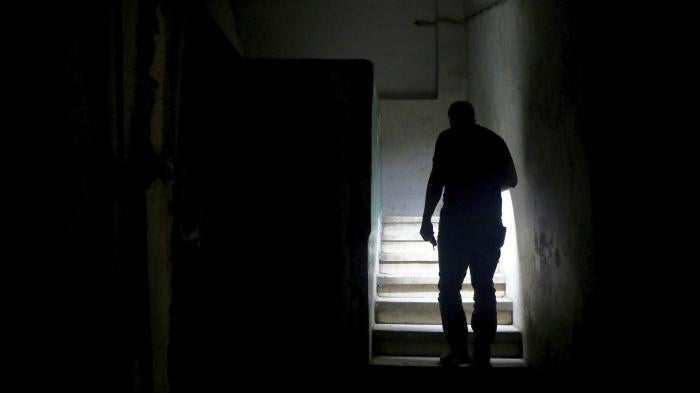 A man uses his mobile phone torch to walk up the stairs to reach his apartment