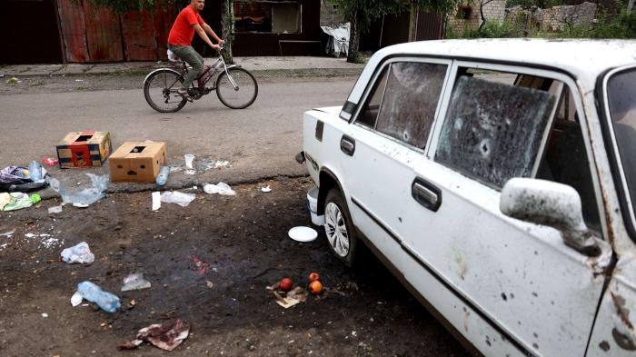 A man rides past a place where a woman was killed by a Russian cluster munition strike in Lyman, Donetsk region, Ukraine on July 8, 2023. 