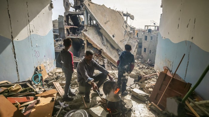 A man cooks inside his damaged apartment in the Khezaa district in Khan Yunis, Gaza, November 25, 2023. 