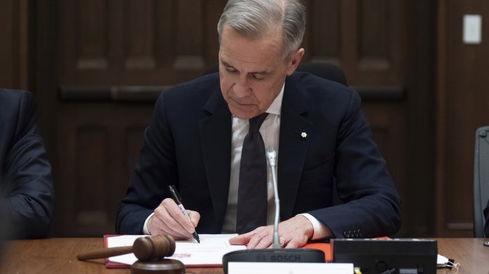 Canadian Prime Minister Mark Carney signs a document during cabinet meeting on Parliament Hill in Ottawa., March 14, 2025.