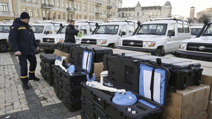 Two men stand by metal detectors used for demining.  