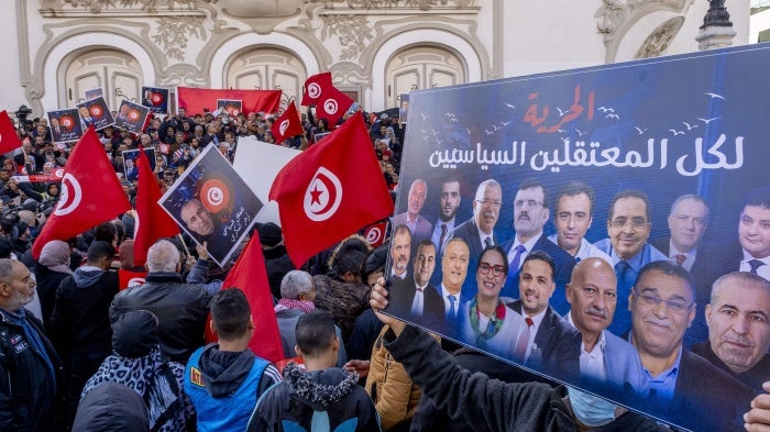 Protesters hold up placards and Tunisian flags