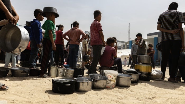 Displaced Palestinians wait to receive a meal in Gaza City, May 17, 2025. 
