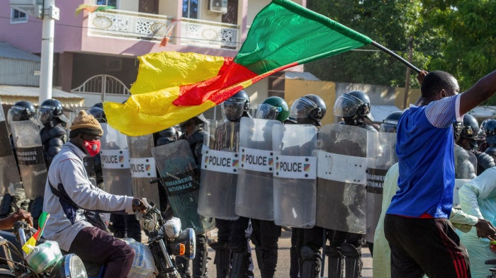 A protester waving a Cameroonian flag approaches police officers as they gather in Garoua on October 26, 2025.