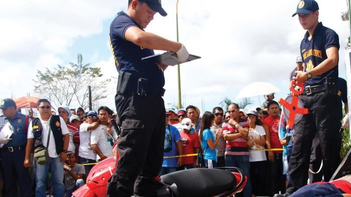 Police officers at the crime scene of the murder of Rogelio Butalid, a broadcast commentator, outside his radio station in Tagum City, in the southern Philippines on December 11, 2013.