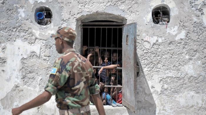 Prisoners at Mogadishu Central Prison watch as a guard walks pass their cell in December 2013. Most of the military court’s hearings in Mogadishu take place inside the prison, which limits access to hearings for relatives and independent monitors.