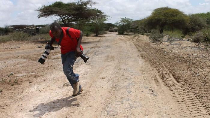 Somali photojournalist runs for cover while reporting on fighting between the Somali government and African Union forces against the Islamist armed group Al-Shabab in the Lower Shabelle region of Somalia, April 2012.