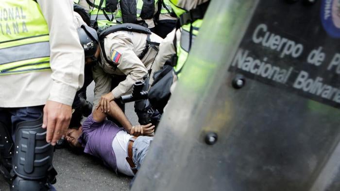 Riot police officers detain a demonstrator during clashes with opposition supporters in a rally to demand a referendum to remove President Nicolás Maduro in Caracas, Venezuela, on May 18, 2016. 