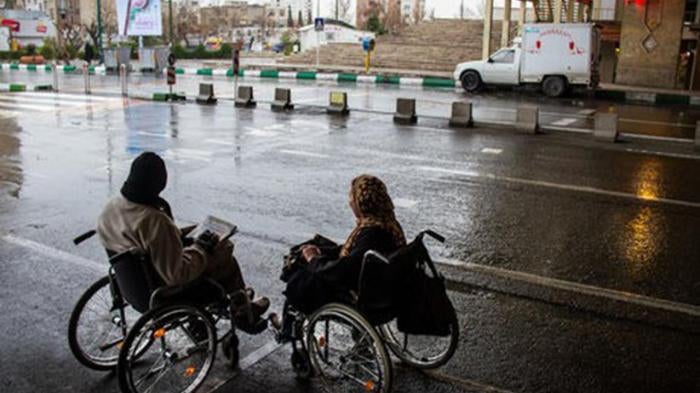 Two women who use wheelchairs attempting to cross a road in Tehran, the capital of Iran. 