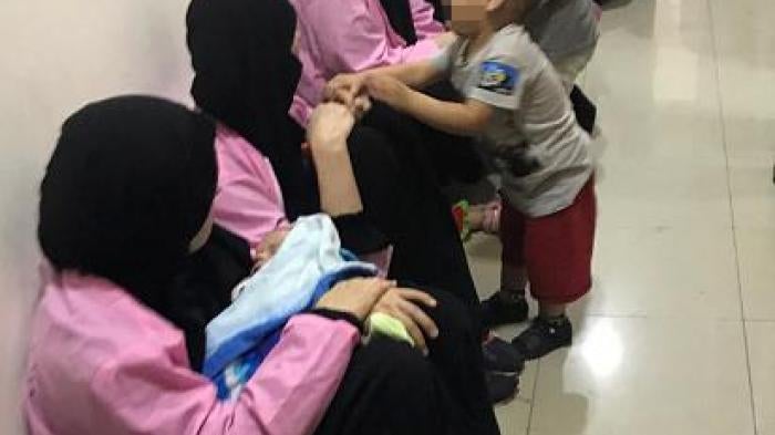Russian women, sentenced to life in prison on grounds of joining ISIS, sit with children in a hallway of Baghdad's Central Criminal Court, April 29, 2018. © 2018 Ammar Karim/AFP/Getty Images