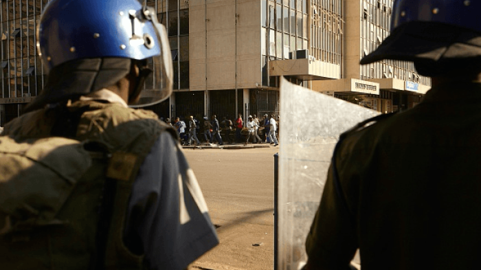Zimbabween soldiers stand guard as citizens run through the Harare's streets, on August 1, 2018. 