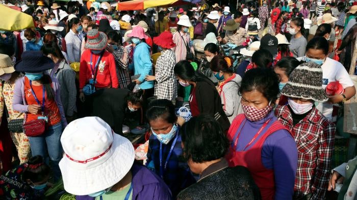 Garment factory workers wear face masks as they walk out at the end of their work shift March 20, 2020, near Phnom Penh, Cambodia.