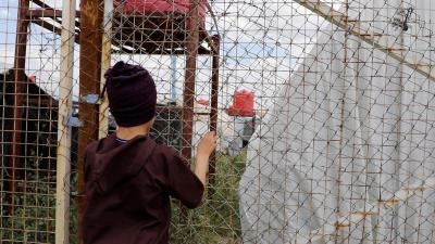 A boy stares through a fence