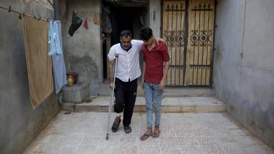 Abdel Karim Bastin, 49, injured in the bombardment of the village Termanin on October 6, leans on his son in front of their home, Syria, October 14, 2023. Bastin lost his nephew in the attack.