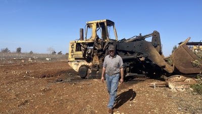 Ibrahim Karim, standing in front of one of the damaged bulldozers from Israeli strikes on August 6, 2025 on Deir Seryan, southern Lebanon.