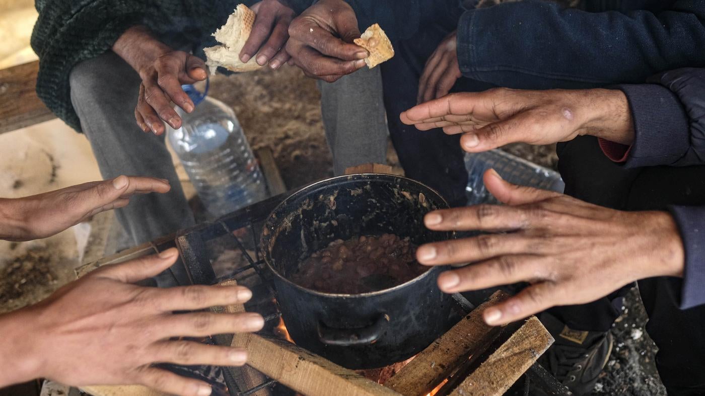Migrants warm their hands above a fire in Bosnia and Herzegovina, January 11, 2021.
