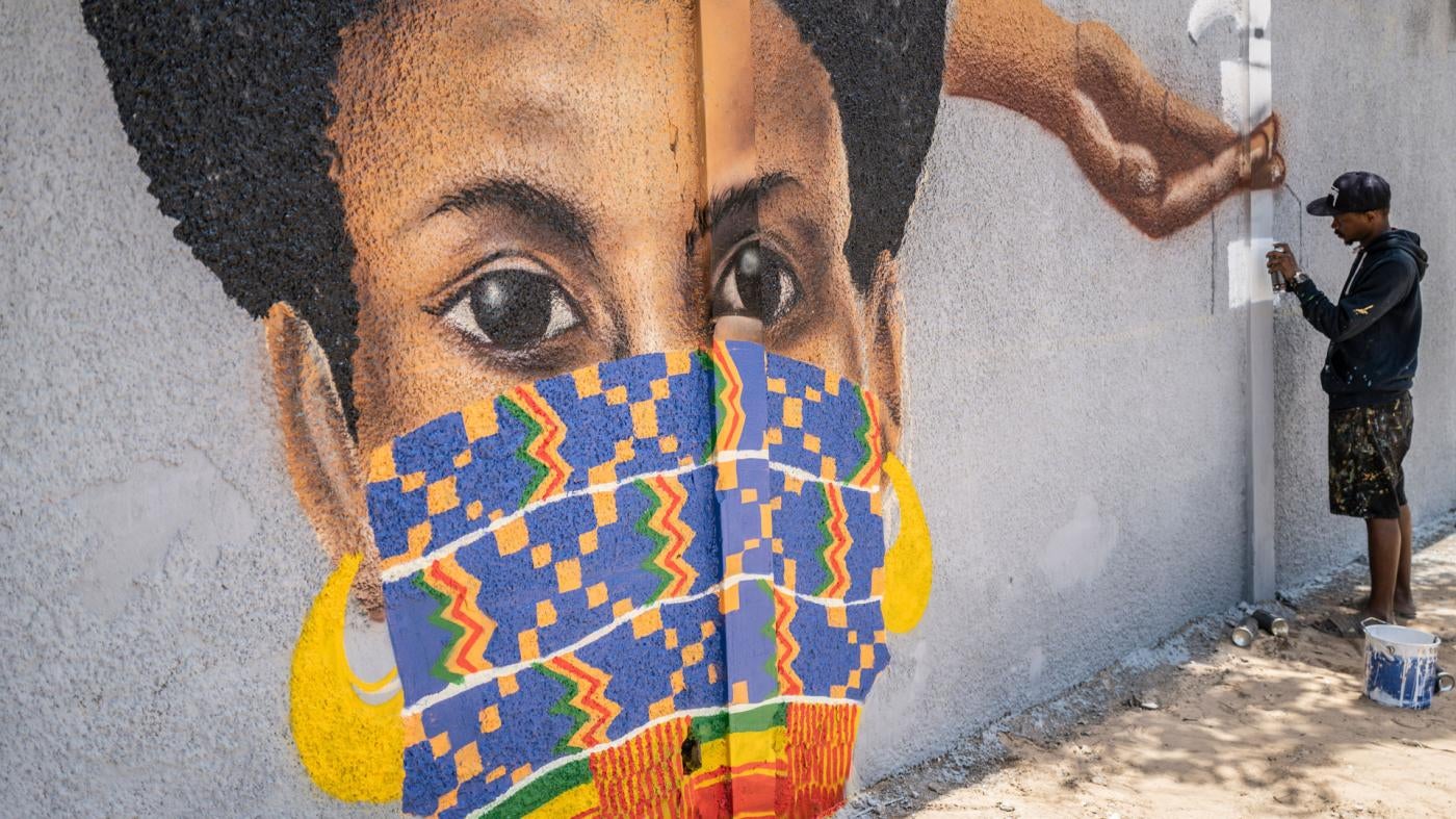 A member of the Senegalese graffiti collective "RBS CREW" paints informational murals advising how to stop the spread of the new coronavirus, on the wall of a high school in the Parcelles Assainies neighborhood of Dakar, Senegal, March 25, 2020. 