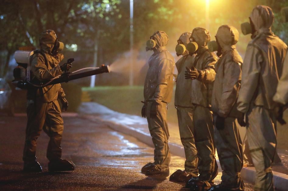 Servicemen of Belarus Ministry of Defence wearing protective gear spray disinfectant on each other after disinfecting a hospital in Minsk