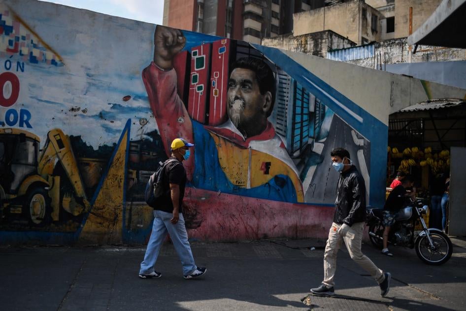 Individuos con mascarillas caminan al lado de un mural con una imagen de Nicolás Maduro en Caracas, el 17 de abril de 2020, en medio de un brote del nuevo coronavirus (COVID-19).