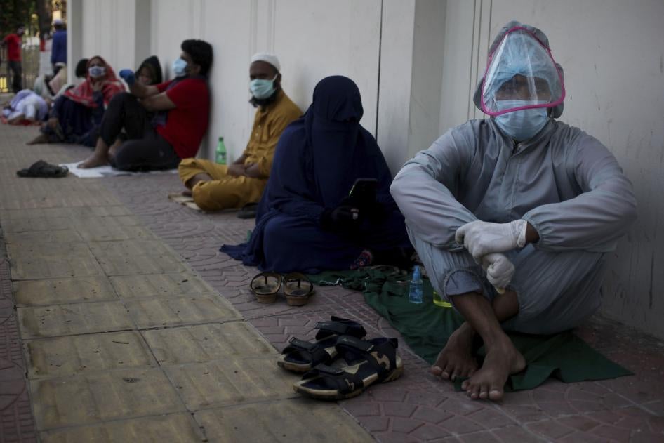 Patients sit on the ground as they wait in queue outside of a hospital for Covid-19 test in Dhaka, Bangladesh on May 16, 2020. 