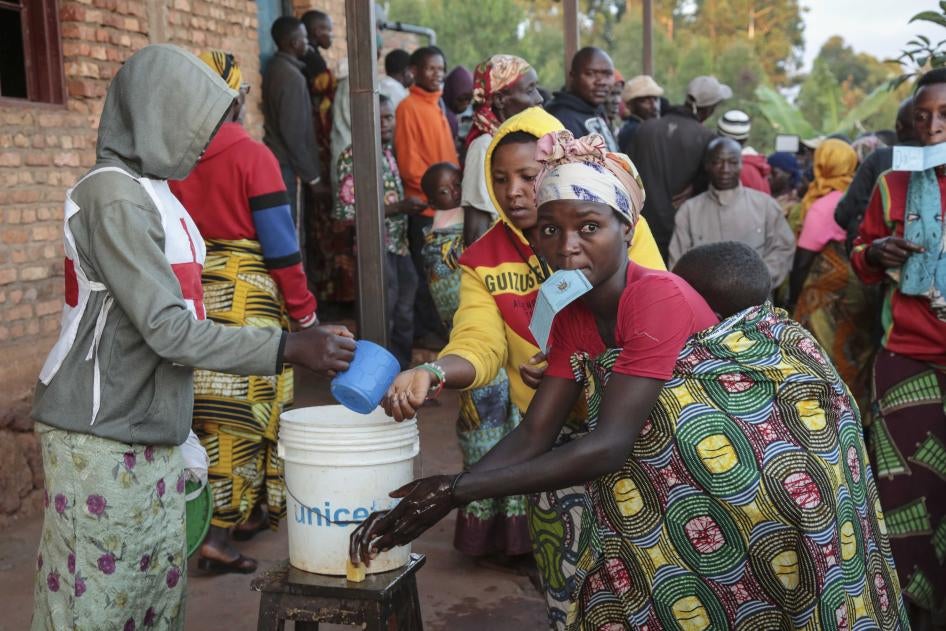 A voter holds her identity card in her mouth as she washes her hands before casting her vote in the presidential election, in Giheta, Gitega province, Burundi, on May 20, 2020.