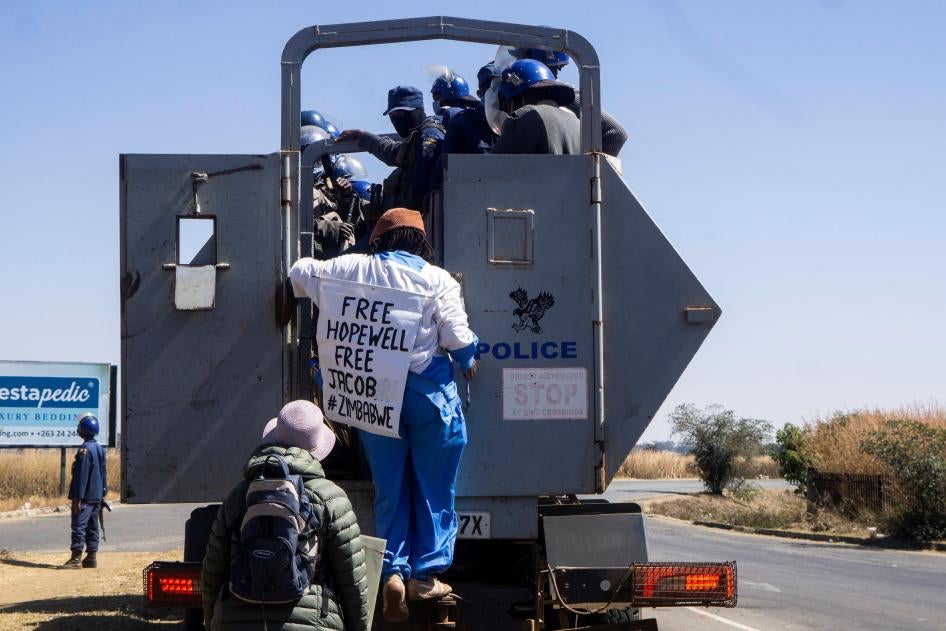 Zimbabwean novelist Tsitsi Dangarembga (center) and her colleague Julie Barnes hold placards as they are arrested during an anti-corruption protest march in Harare, Zimbabwe, on July 31, 2020.  © 2020 ZINYANGE AUNTONY / AFP