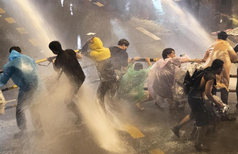 Pro democracy demonstrators face water canons as police try to clear the protest venue in Bangkok, Thailand, Friday, Oct. 16, 2020. 