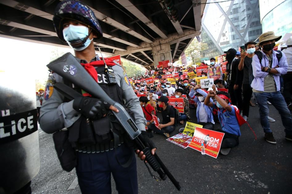 A police officer stands in front of anti-coup protesters in Yangon, Myanmar, February 19, 2021.