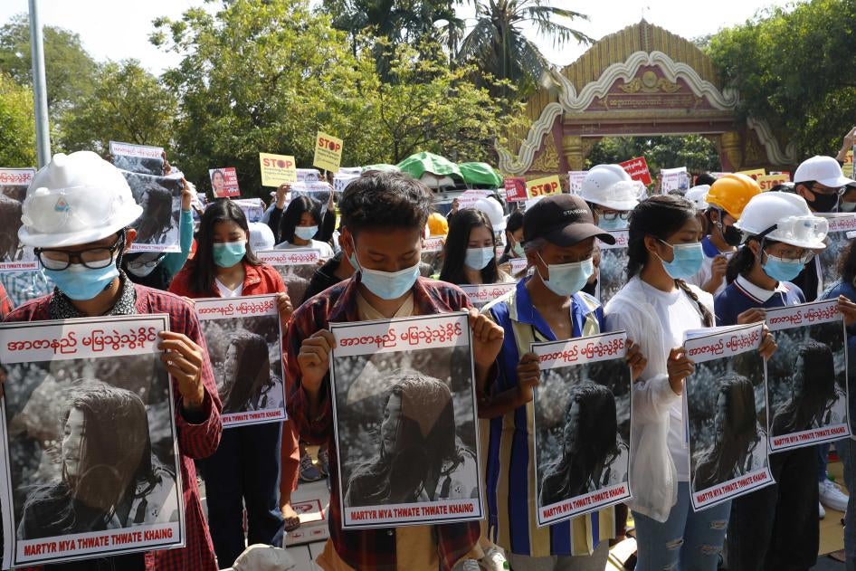 Mandalay University graduates bow their heads as they hold posters of Mya Thwet Thwet Khine, a 19-year-old woman fatally shot by police on February 9 in Naypyidaw, during an anti-coup protest in Mandalay, Myanmar, February 14, 2021. 