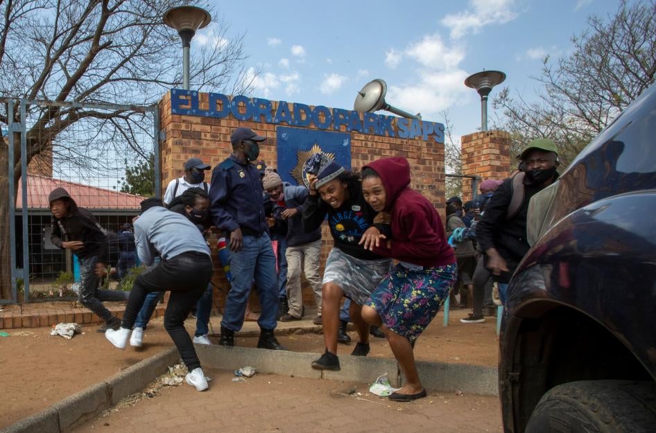 Protesters run for cover as they clash with police at Eldorado Park police station in Johannesburg, South Africa, August 27, 2020. 