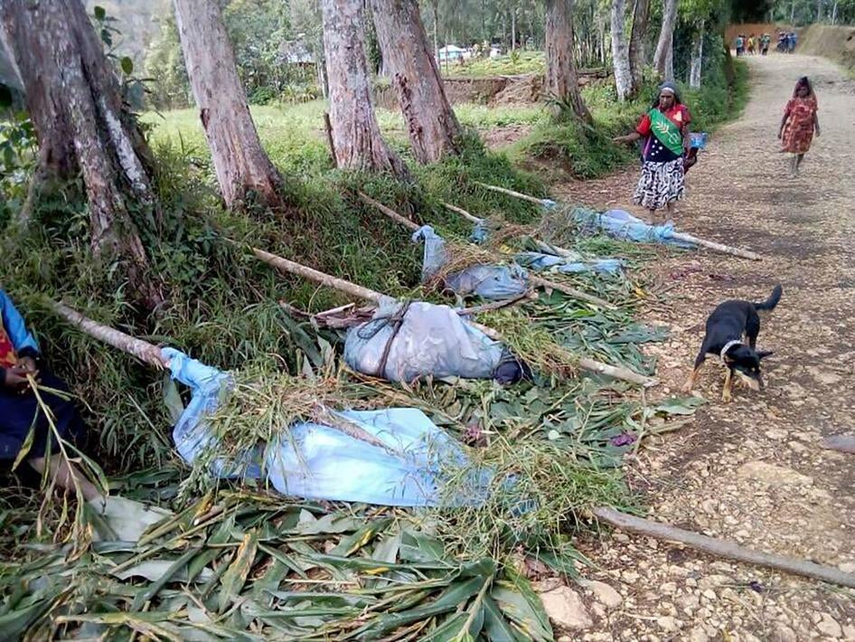 In this July 8, 2019 file photo, locals stand near the bodies of victims recovered following tribal violence in Karida, Papua New Guinea.