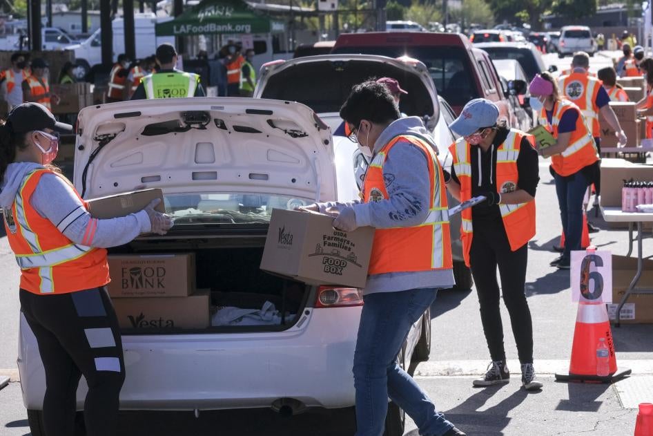 Voluntarios ponen alimentos en el maletero de automóviles durante la campaña de distribución vehicular de alimentos “Let’s Feed LA County” organizada por Los Angeles Regional Food Bank y la Oficina de la Supervisora Hilda Solís el 23 de febrero de 2021, en La Puente, California. 