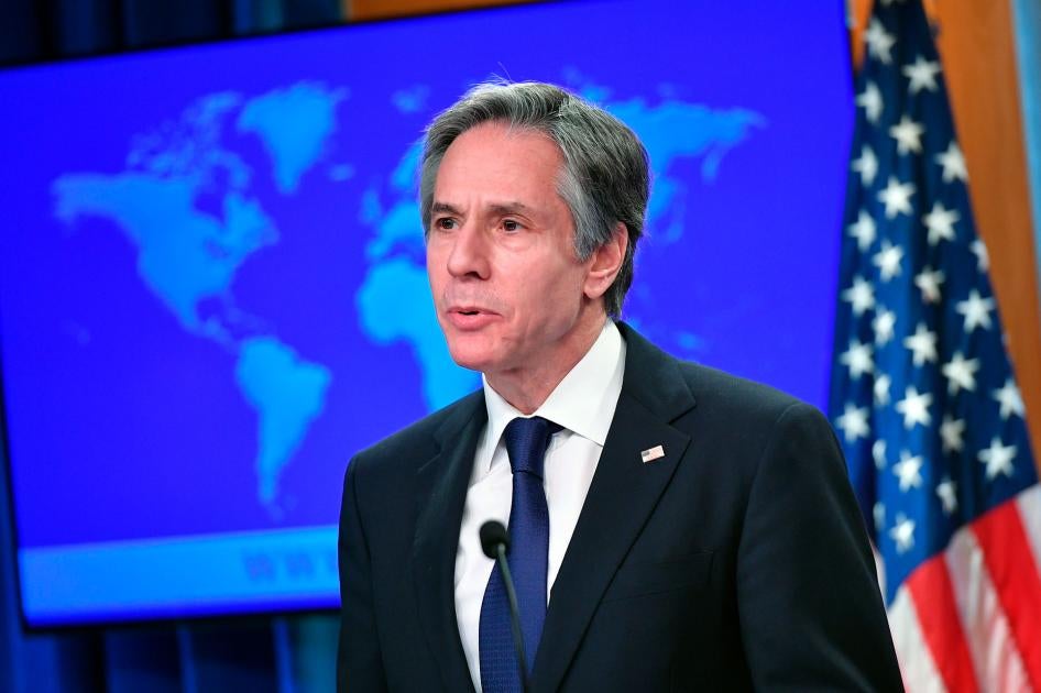 Secretary of State Antony Blinken speaks at the State Department in Washington, standing in front of a world map and a US flag.