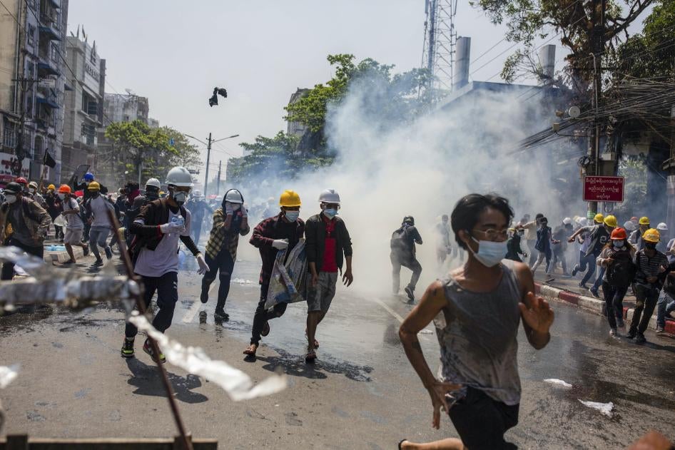 Anti-coup protesters run from teargas deployed by the police during a demonstration in Yangon, Myanmar, March 1, 2021.