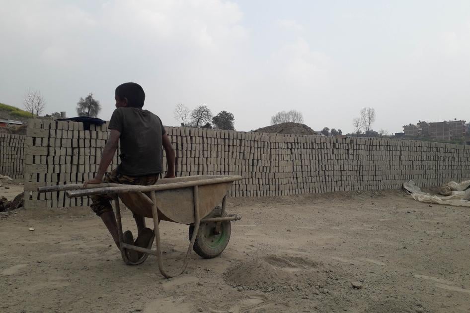 A boy sits atop a wheel barrow