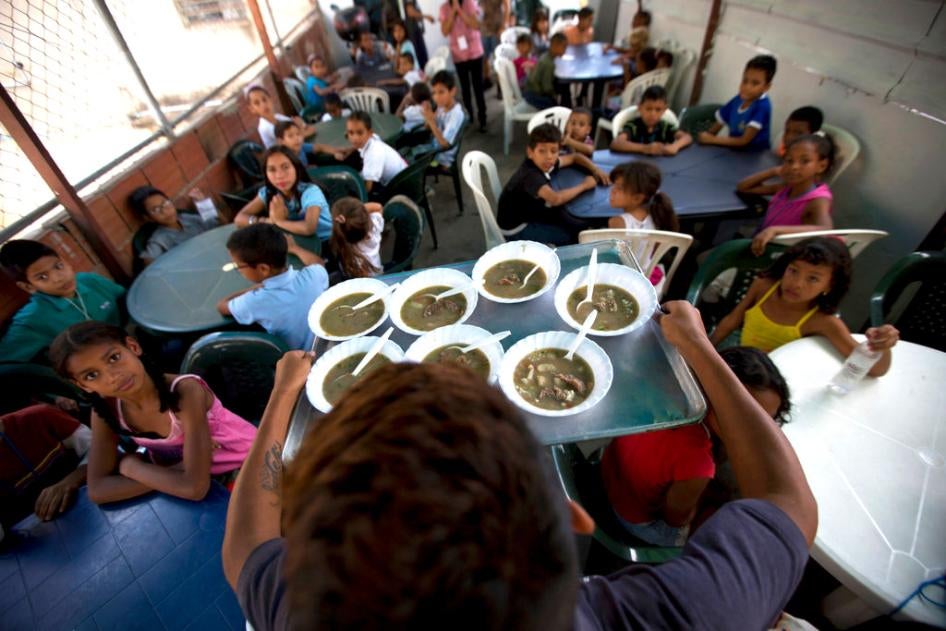 In this Dec. 12, 2017 photo, children watch their free meal arrive to be served at a soup kitchen sponsored by the opposition in Caracas, Venezuela.