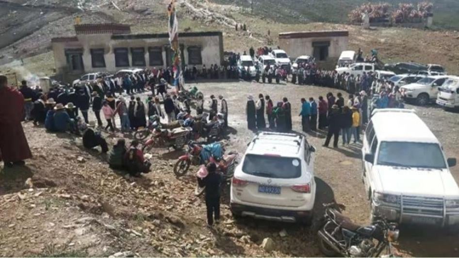 A large crowd standing in a circle outside of a monastery building