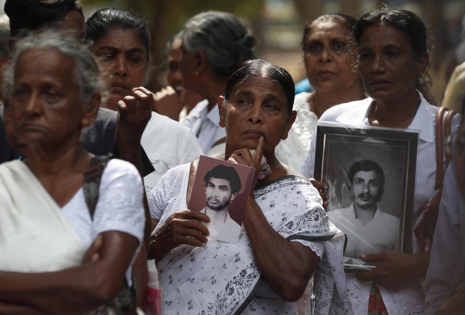 A group of women holding black-and-white photos of men