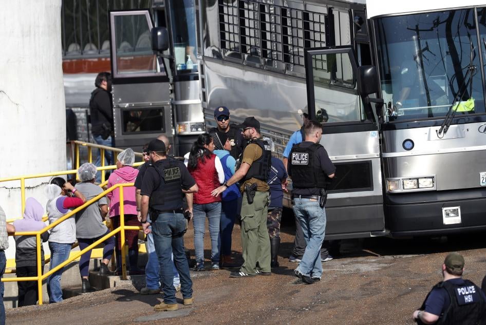 Uniformed police officers put people on a bus