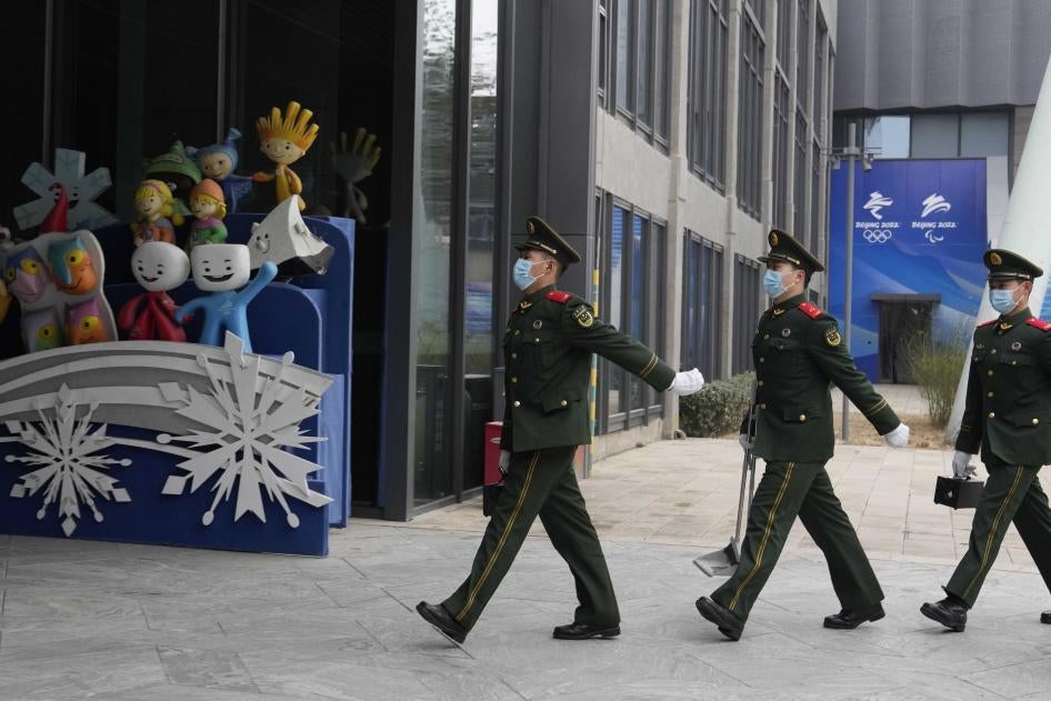Chinese paramilitary police march past mascots from prior Winter Olympics displayed at Shougang Park in Beijing, China, January 21, 2022. © 2022 AP Photo/Ng Han Guan