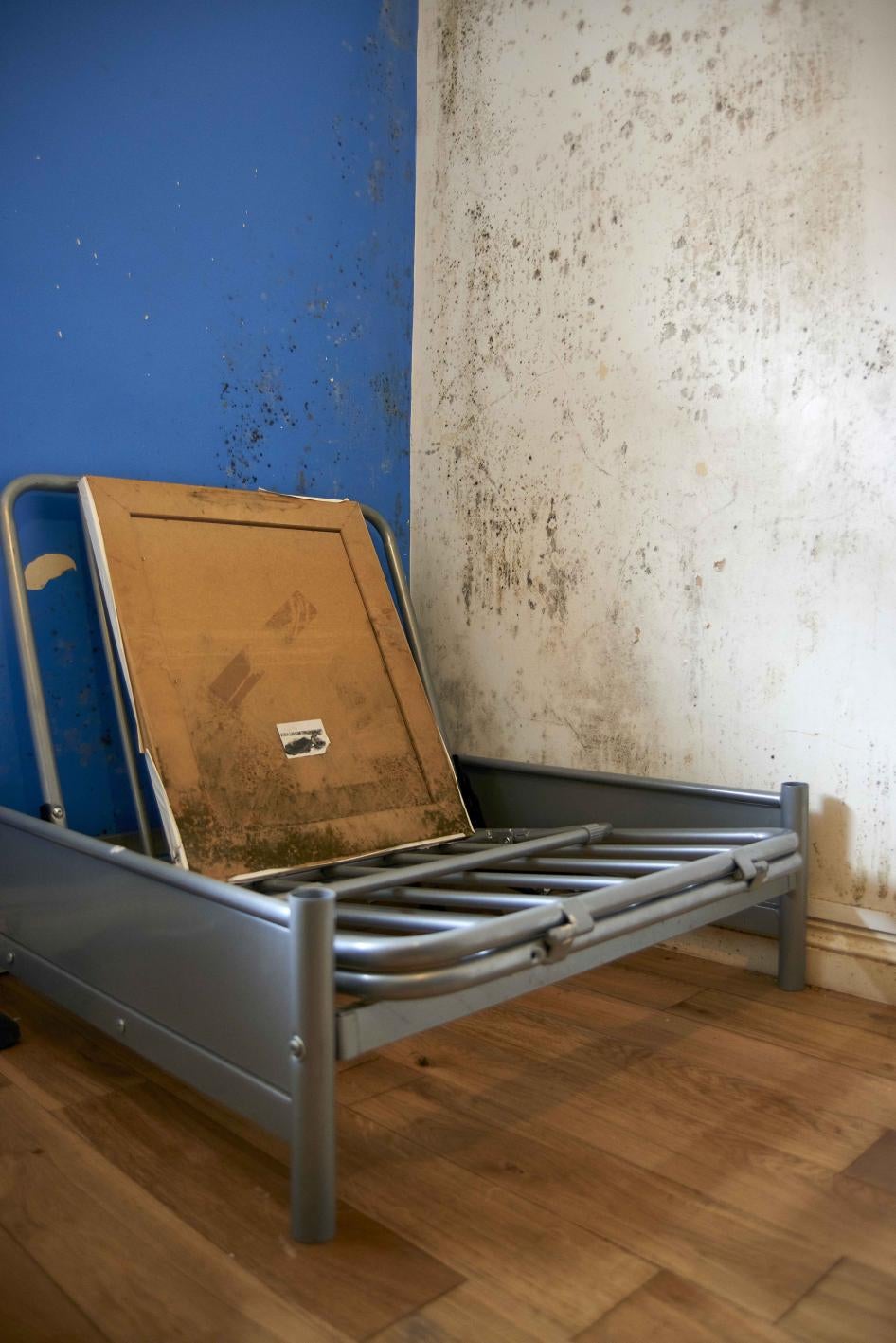 an empty piece of furniture against a mold-covered wall 