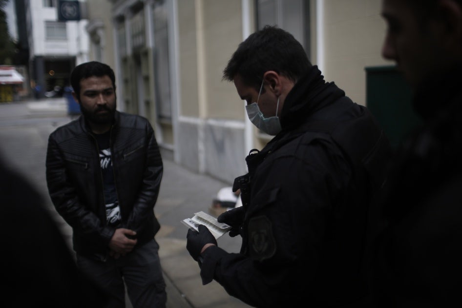 Police officers check the documents and permissions of people in the streets of Athens, Greece, March 23, 2020. 