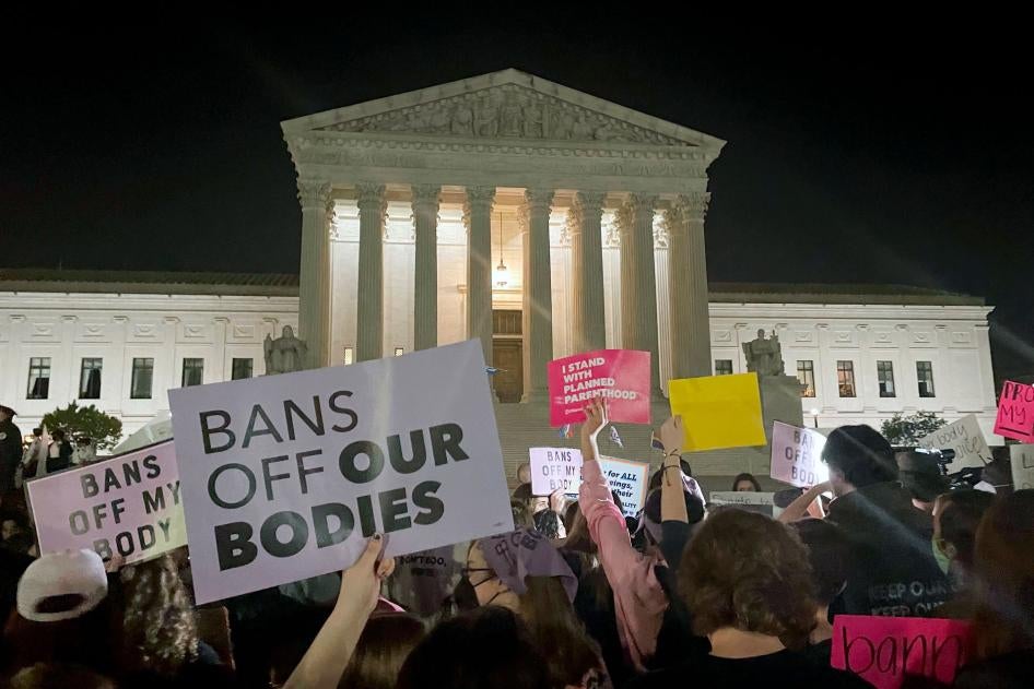 People protest holding signs outside of the US Supreme Court at night