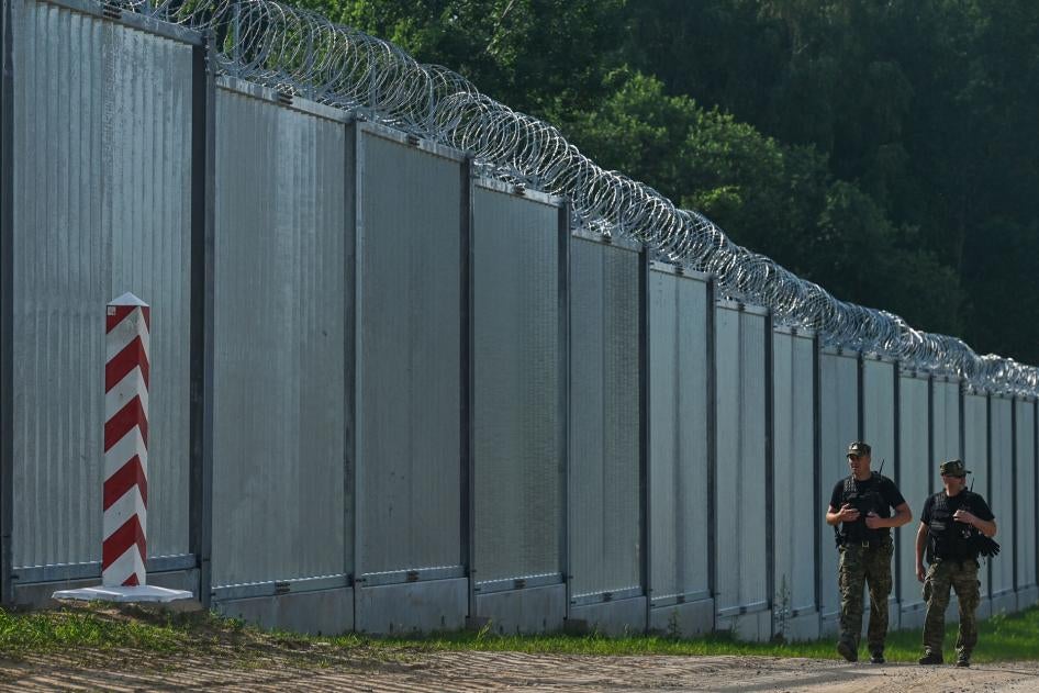 Polish border guards patrol along a fence