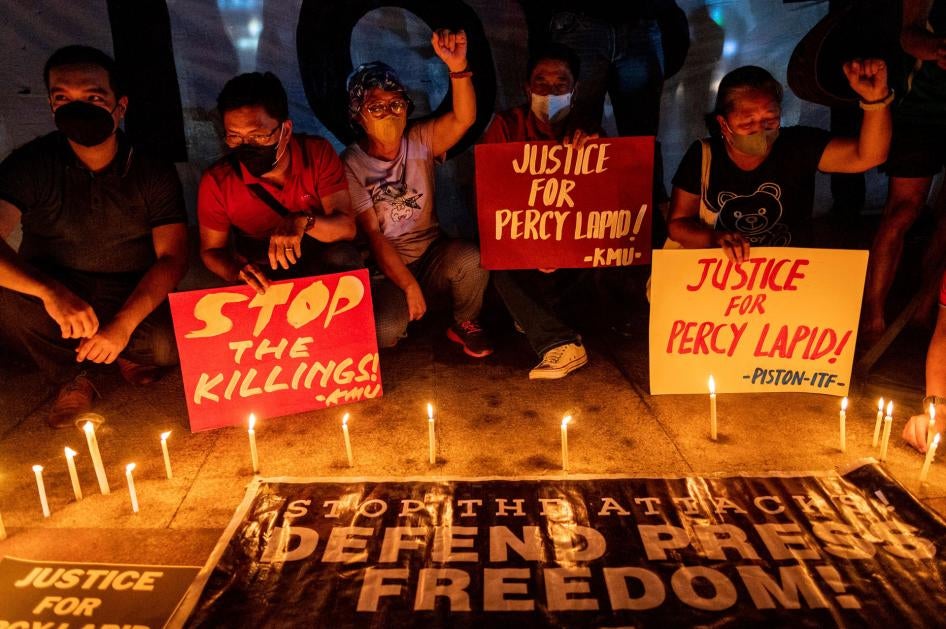 People light candles and hold signs during a rally