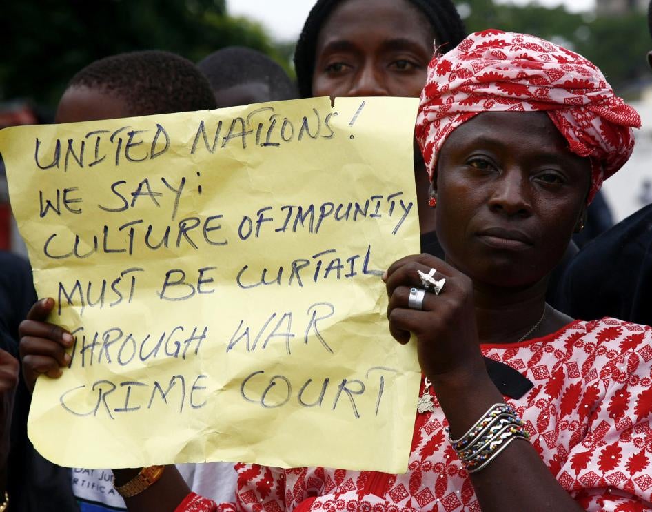 A woman holds a placard during a peaceful demonstration in the Liberian capital Monrovia, July 4, 2006, calling on the visiting U.N. Secretary General Kofi Annan to establish a war Crimes court in Liberia as a means to bring justice to the country. 
