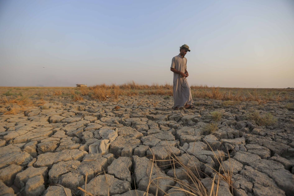 A fisherman walks across a dried patch of land in the marshes of southern Iraq in Dhi Qar province, September 2, 2022. Iraq's marshlands are rapidly receding due to drought, domestic water mismanagement, and diversion from neighboring countries.