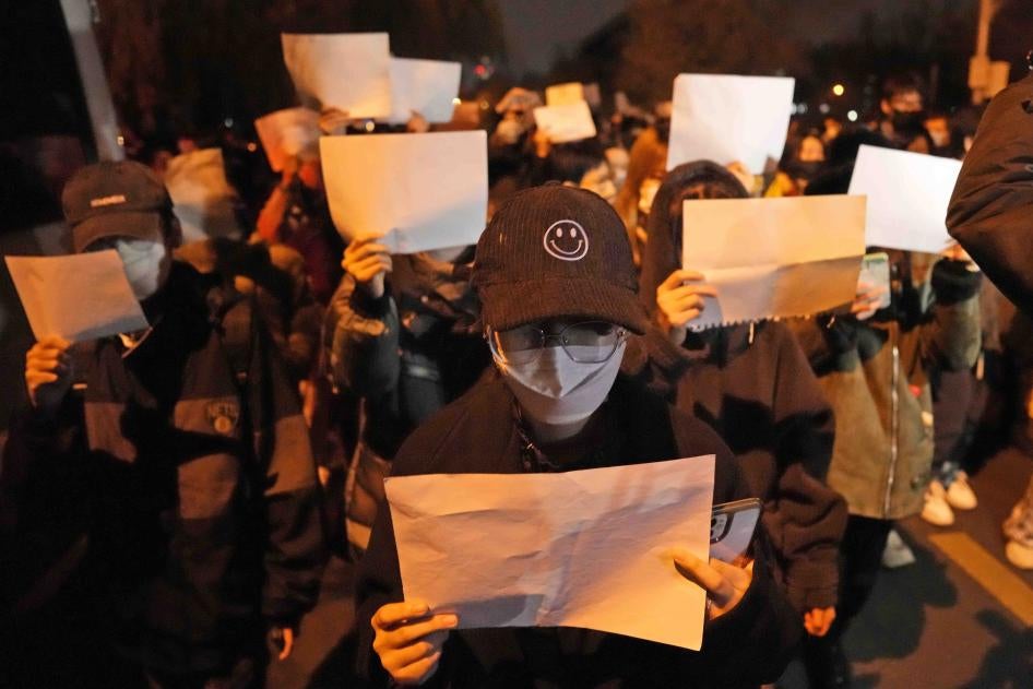 Protesters hold up blank papers and chant slogans as they march in protest in Beijing