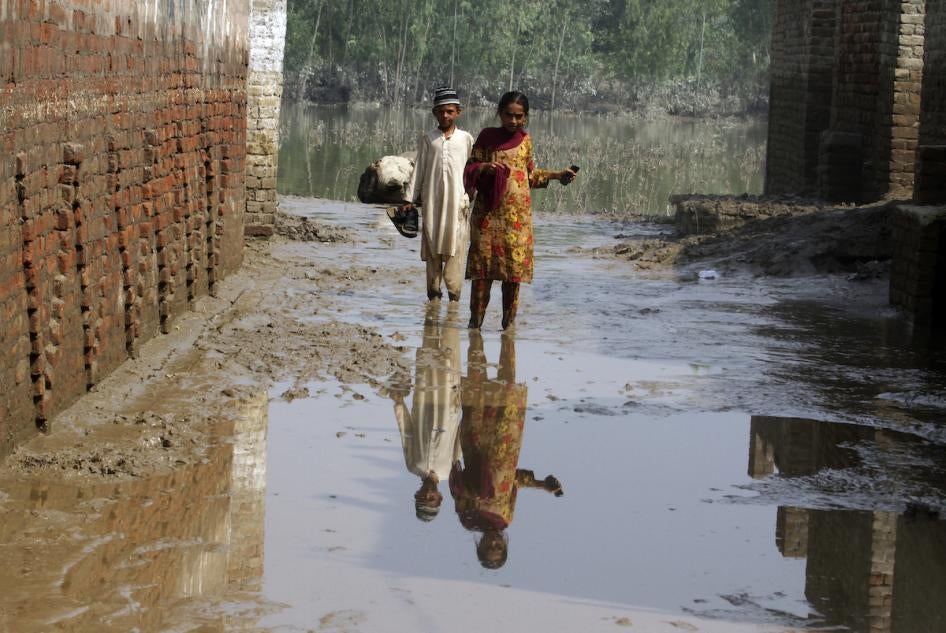 Two children wade through mud near their flood-hit home in Charsadda, Pakistan.