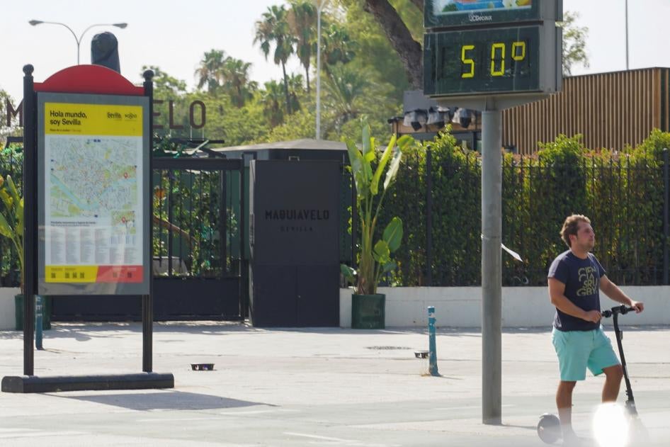 A sign in Paseo de las Delicias, Seville (Andalusia, Spain) on July 25, 2022, displaying the high temperature of 50 degrees Celsius (122.0 degrees Fahrenheit), and a man using his scooter.